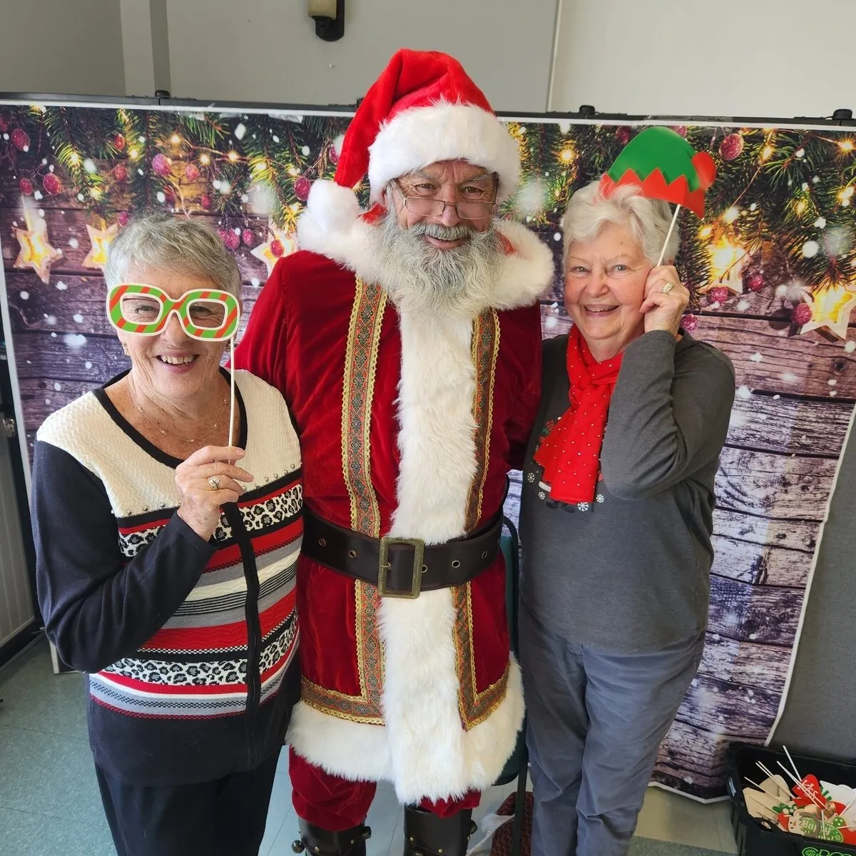 Two women posing with Santa Claus at a holiday celebration
