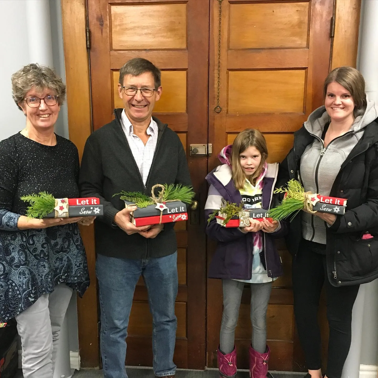 People holding decorated gift boxes at a library holiday event